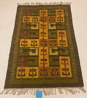 Full view of the rug laid flat on the floor showing overall pattern, fringe, and color palette.