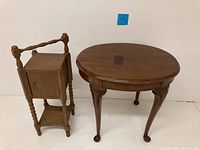 Full view of the vintage wooden humidor cabinet and Drexel Legacy cherry oval side table side by side against a wall.