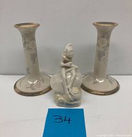 Front view of the two Lenox porcelain candle sticks with floral pattern and gold trim beside the Belleek clown figurine.