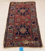Full view of vintage Turkish wool rug showing geometric designs in blue, red, beige and light blue tones with visible wear.