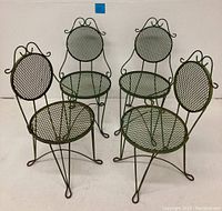 Set of four vintage wrought iron chairs shown with rusted green paint, circular mesh seats and backs, decorative curved wrought iron details.