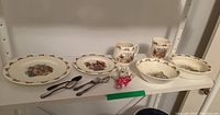 Full set on shelf showing all dishes, cups, figurine and flatware.