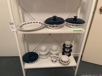 Overall view of Ridgeway Contessa dishes and Mikasa Sophisticate cups and saucers on two shelves showing platters, covered bowls, pitcher, cups, saucers and bowls.