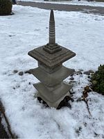 Full view of weathered pagoda standing in snow, showing layered roof design and pointed top finial.