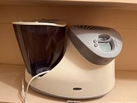 Side angled photo of white and gray Honeywell humidifier with translucent water tank, power cord connected, showing digital display and buttons.