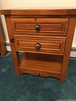 Full front view of the wooden nightstand showing two drawers with metal handles and open shelf beneath