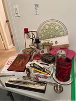 Photo showing the full large lot on a white table including tray, candles, candlesticks, books, cake servers, and assorted small decorative items