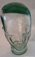 Front view of heavy glass mannequin head showing facial details and slight green tint