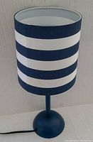 Front view of the blue nightstand lamp showing navy and white horizontal stripes on the cylindrical shade and solid navy blue base.