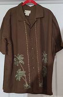 Front view of brown Hawaiian shirt with embroidered palm trees, button front and short sleeves.