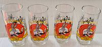 Four clear glasses featuring Bugs Bunny in a colorful 50 years birthday design, showing front views of all glasses in the set.