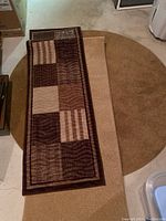 Photo showing the round solid brown area rug underneath two rectangular patterned runners, brown and beige tones.