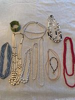Photo showing nine pieces of assorted beaded jewelry laid out on a fabric background.