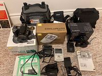 Overview of all cameras, boxes, bags and accessories on carpeted floor