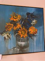 Full view of the sunflower painting showing the orange-yellow sunflowers with dark leaves in a reflective vase on a blue background.