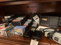 Shelf view of entire lot: recorders, players, headphones, carrying case, cassette tapes in bins and boxes