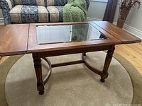 Full view of the wooden coffee table showing drop leaf extension and glass center insert.