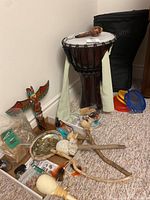 Photo showing the entire set including drum, case, carved rattle, tambourines, wooden totem, and other accessories arranged on carpet.