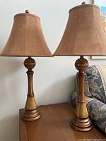 Full view of the pair of tall lamps with shades, showing gold bases and soft brown shades.