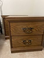 Front and angled view of two matching wooden nightstands showing overall shape and handles.