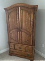 Full view of the Palliser armoire showing double doors and two large exterior drawers below.