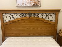 Front view of queen size headboard showing wood panel bottom section and decorative black metal scrollwork with top molding detail.