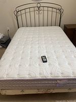 Full view of double bed with mattress, remote on top, frame and headboard visible