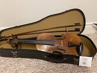 Violin displayed inside open black case with bow resting on top, showing overall wear on the violin.