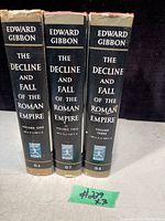 Set of 3 vintage hardcover books by Edward Gibbon titled The Decline and Fall of the Roman Empire with volume numbers one, two, and three visible on spine. Black spine labels with white text and logos.