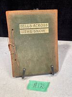 Front view of antique book with worn green suede cover and sewn binding, title on paper labels attached to front.