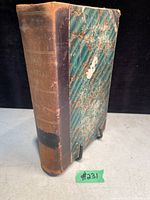 Front and spine cover showing marbled and worn binding of antique book.