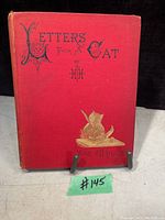 Front cover of the antique book Letters from a Cat, red hardcover with gold and black lettering and illustration of a cat.