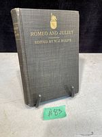 Front cover of the antique Romeo and Juliet book showing grey cloth hardcover with gold embossed text and emblem.