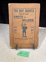 Front cover of antique The Boy Scouts book, showing title, price, and illustration of a scout on a brown cover