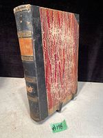 Front cover of antique book showing leather spine with gilt decorations and marbled cover boards.
