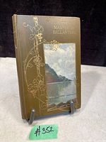 Front cover of the antique book showing brown hardcover with gold embossing and a coastal scenic illustration.
