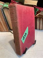 Red cloth hardcover book with gold embossed text on spine showing the title and author.