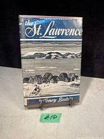 Front cover of 'The St. Lawrence' book showing a winter village scene with mountains in the background.
