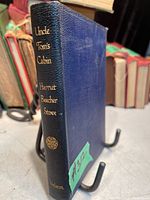 Front side angled view of the antique Uncle Tom's Cabin book showing blue textured cover with gold embossed title and author on spine.
