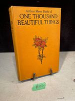 Front cover of the yellow-orange hardcover book titled 'Arthur Mee's Book of One Thousand Beautiful Things' showing an illustration of roses and the title in black.