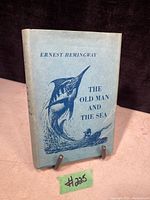 Blue dust jacket showing the front cover of the book with title and illustration of marlin and fisherman