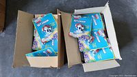 Two open cardboard boxes containing multiple blue-packaged Hawaiian Punch keychains stacked loosely inside.