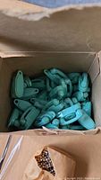 View inside box showing multiple baby blue plastic miniature telephone keychain phones loosely packed.
