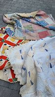 Three vintage/antique patchwork quilts layered showing patterns and condition details