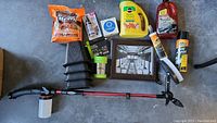 Overview of assorted car wash and household items showing cleaning liquids, brush, spray gun, funnel, framed photo, and other small items