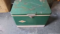 Front view of the green vintage Coleman cooler showing embossed diamond design on lid, latch, and Coleman logo on the body.