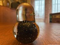 Close-up view of the clear and black art glass bird figurine showing air bubble details inside the black glass section and smooth rounded head shape.