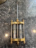 Top view of pendulum showing brass frame, glass tubes with mercury, and connecting metal rods.