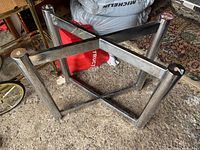 Chrome rectangular table base with four cylindrical legs and X-shaped reinforcement braces viewed from above on carpet.