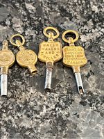 Photo showing four Victorian pocket watch keys with brass tops and metal shafts, placed on a dark granite counter